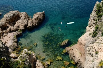 Cliffside view of turquoise cove with kayakers and swimmers below