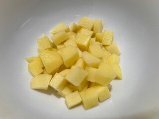 Fresh peeled potatoes that have been cut into small pieces, isolated on white background