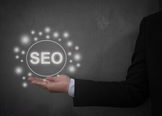 Businessman holding a glowing SEO concept icon with vibrant lights, symbolizing innovation, search engine optimization, and digital marketing strategies. Ideal for technology and business themes