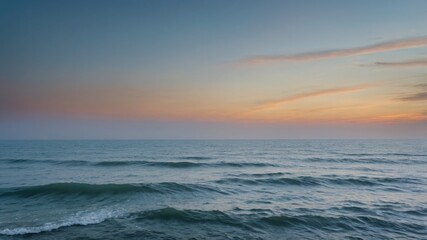 Obraz premium Calm ocean waves under colorful early sky. Blue water with light ripple under orange sky at dawn. Ocean skyline with faded clouds.