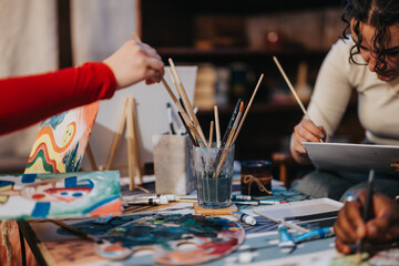 Two individuals engaged in a shared painting activity, using art supplies on a table in a cozy setting, fostering artistic creativity and collaboration.
