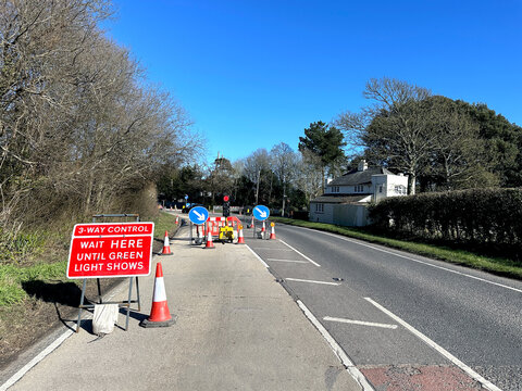 Temporary traffic lights with a when red light shows wait here sign on a residential street.