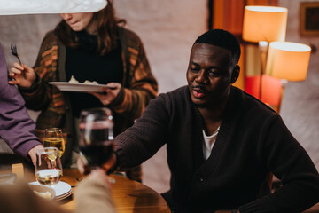 Group of friends gathered around a table enjoying dinner and drinks in a relaxed setting.
