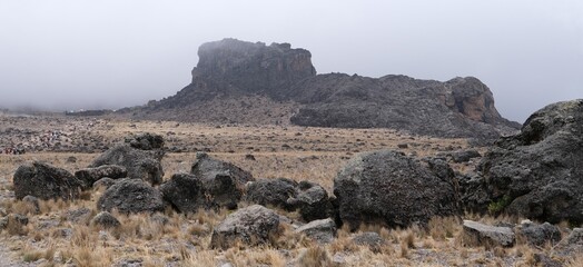 Kilimanjaro, Tanzania: Misty scenery of Lava Tower and silhouettes of trekking people. Machame Route, trail from Shira Camp to Barranco Camp. © Iwona
