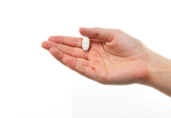 Hand holding medicine pill against a plain background  