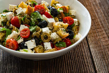 Greek style salad - tomatoes with feta cheese, bread and olives on wooden table