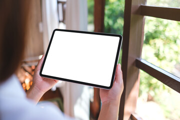 Mockup image of a woman holding tablet with blank desktop white screen at home