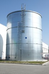 Metalowy zbiornik przeciwpożarowy z widoczną drabiną pionową prowadzącą na dach zbiornika