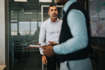 A group of multiracial business people engaged in a dynamic meeting. The scene captures thoughtful discussion, teamwork, and professional interaction in a modern office environment.