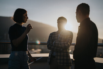 A diverse group of business people brainstorms together on a rooftop at sunset, creating a dynamic atmosphere of innovation and collaboration.