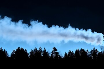Smoke plumes above a dark silhouette of forested tree tops