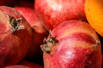 Vibrant pomegranates gleaming in the morning sun at an open-air market in autumn