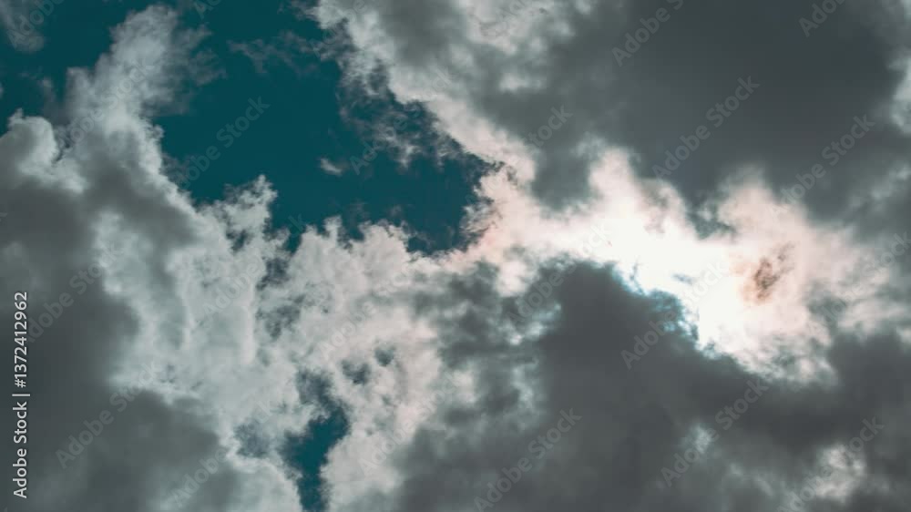Wall mural sunray shine through dark clouds in cloudy blue sky. natural background clouds time lapse. cloudy sk