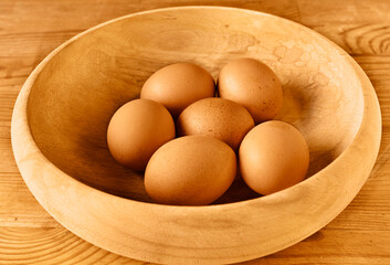 Brown eggs in wooden bowl