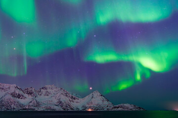 Northern lights above snow covered mountains including Klubbnesviktinden in Oksfjorden in Finnmark, Northern Norway on 23 March 2025.