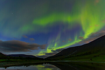 Obraz premium Aurora in the night sky cut the mountains, reflected in the water. Yamal. Russia