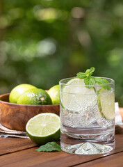 Glass of sparkling water with lime slices and mint leaves