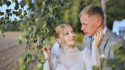 Romantic newlyweds embracing beneath birch tree, expressing deep connection during intimate wedding...