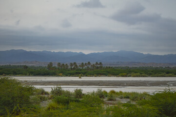 clouds over lake in the mountains, small garden near river palm dates tree