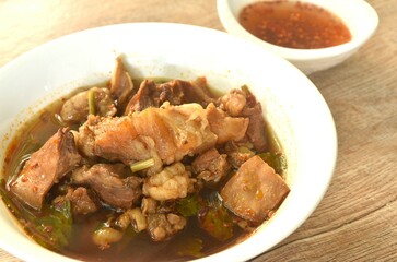 boiled braised beef meat and tendon in herb brown soup on bowl dipping spicy chili sauce 