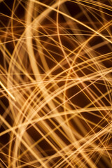 Dynamic abstract light painting with golden glowing streaks of motion captured through long...