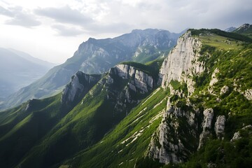 Naklejka premium Rugged mountain range; steep, green forested slopes under cloudy sky