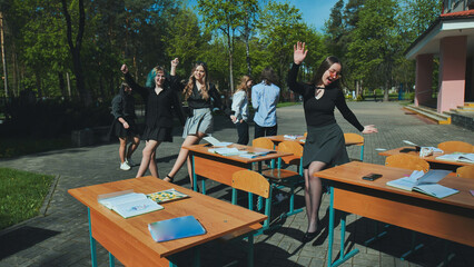 High school students happily dancing and enjoying themselves in the schoolyard on a sunny day