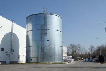 Metalowy zbiornik przeciwpożarowy z widoczną drabiną pionową prowadzącą na dach zbiornika