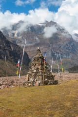 Blessing stone stupa and praying flag with the beautiful mountain covered with clouds.