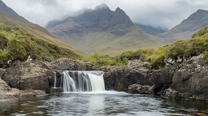Majestic waterfall in the Fairy Pools, Glen Brittle, Isle of Skye, Scotland, cascading over rugged rocks with a famous cracked mountain in the background on a misty autumn day.