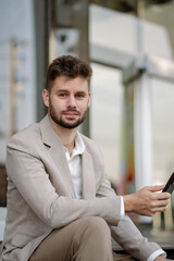 Fototapeta premium Portrait of a successful businessman using smartphone, looking to camera.