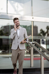 Fototapeta premium Young Businessman Walking and Talking on Mobile Phone in City.