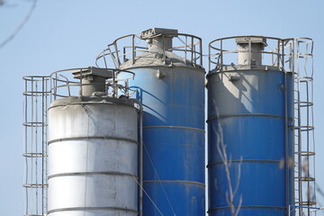 Silosy cementowni z widocznymi drabinami pionowymi