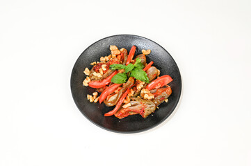 Makdous vibrant roasted eggplant salad with fresh tomatoes, crunchy walnuts, and aromatic mint leaves served on a black plate, beautifully garnished with sprigs of fresh herbs