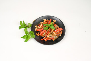 Makdous vibrant roasted eggplant salad with fresh tomatoes, crunchy walnuts, and aromatic mint leaves served on a black plate, beautifully garnished with sprigs of fresh herbs