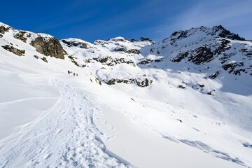 Snow-covered peaks with hikers under blue sky