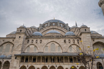 Majestic view of the S&uuml;leymaniye Mosque in Istanbul showcasing its grand Ottoman architecture, cascading domes, intricate stonework, and serene atmosphere under a cloudy sky with a hint of gold leaves