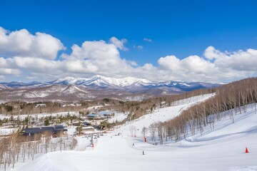 Snowy mountain slope, blue sky, and white clouds on a sunny winter day