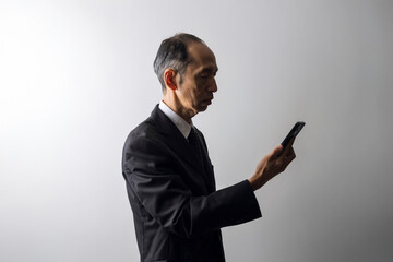 スマートフォンを持ったスーツ姿の中高年男性