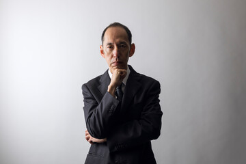 頬杖をつくスーツの日本人の中高年男性