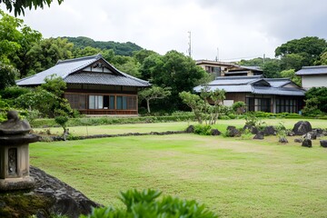 Fototapeta premium Traditional Japanese homes surround bright grassy lawn and stone garden