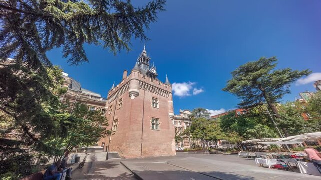 Renaissance dungeon clock tower and classical brick facade of the Capitole timelapse hyperlapse, city hall of Toulouse, France, surrounded by trees in Charles de Gaulle Square under a blue cloudy sky