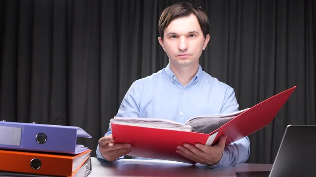 Office worker reading documents in a red folder at night