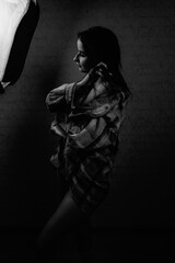 Portrait of a young beautiful dark-haired girl in a studio in a low key. Black and white photo.