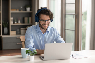 Virtual interaction. Happy smiling gen z man office worker freelancer student in wireless earphones communicate with colleagues on video conference get knowledge in online class webinar using notebook