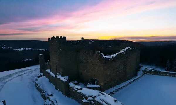 Aerial view of beautiful historic castle ruins on the hill in winter at sunset. Tenczyn Castle in Rudno, Poland. Filmed on FPV drone