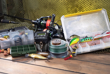 Sport fishing equipment on a table in a studio in a composition, against a wooden background and a fishing net.