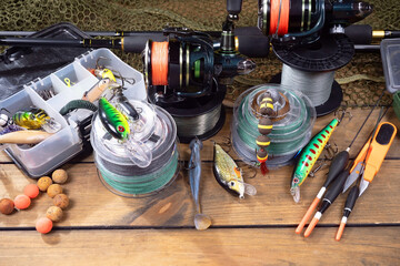 Sport fishing equipment on a table in a studio in a composition, against a wooden background and a fishing net.