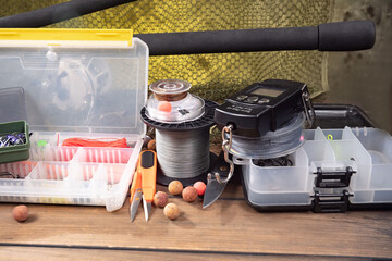 Sport fishing equipment on a table in a studio in a composition, against a wooden background and a fishing net.