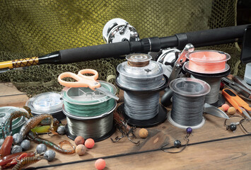 Sport fishing equipment on a table in a studio in a composition, against a wooden background and a fishing net.
